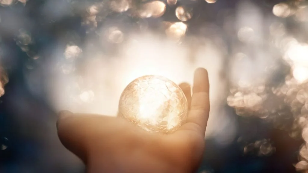 Una mano aperta che tiene una sfera di luce